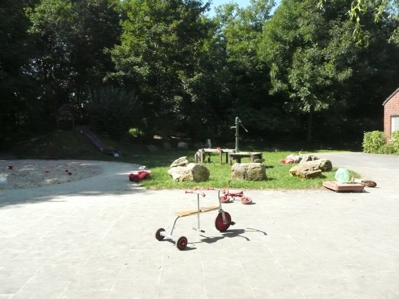 Naturnahes Außengelände mit Sandspielbereich, Hügelrutsche und Wasserpumpe